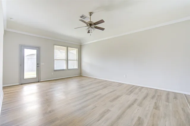 an empty room with wooden floor fan and windows