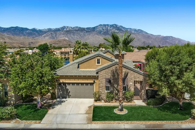a view of a white house with a big yard and large tree
