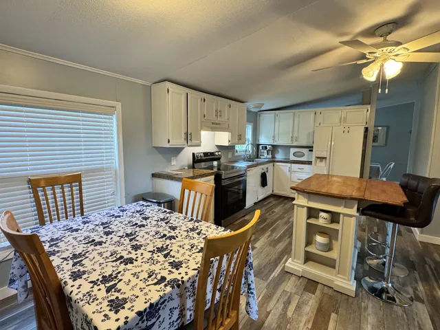 a kitchen with kitchen island a stove a sink a refrigerator dining table and chairs