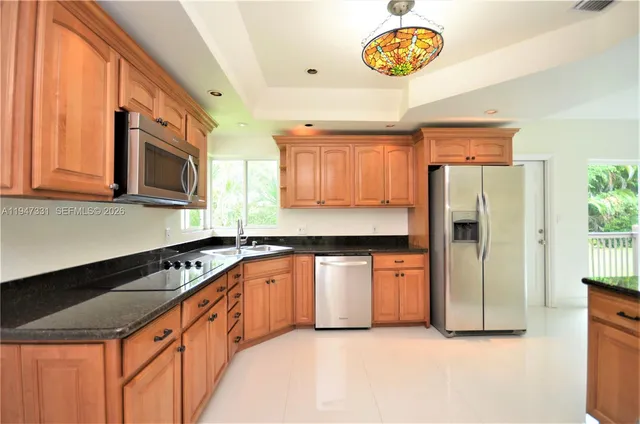 a kitchen with granite countertop stainless steel appliances a stove top oven a sink a counter space and cabinets
