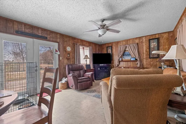 a living room with furniture a ceiling fan a fireplace and a flat screen tv