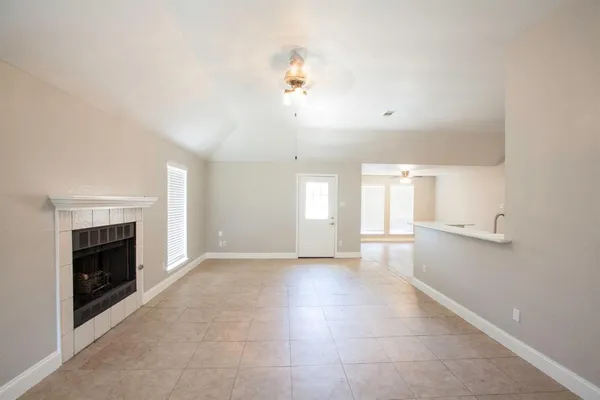 an empty room with windows and fireplace