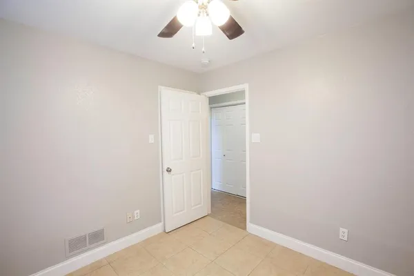 an empty room with a ceiling fan and carpet