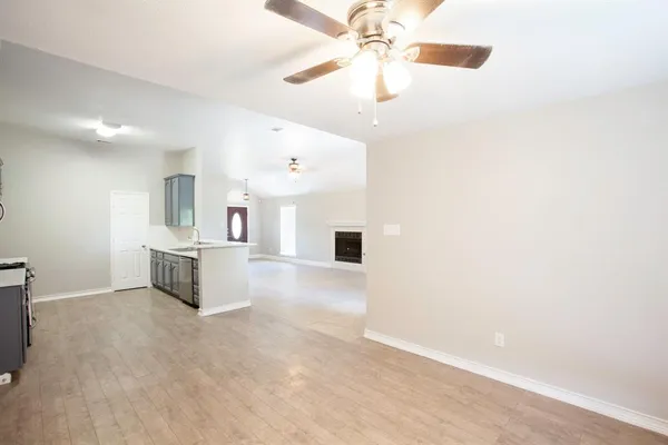 an empty room with a kitchen and a ceiling fan