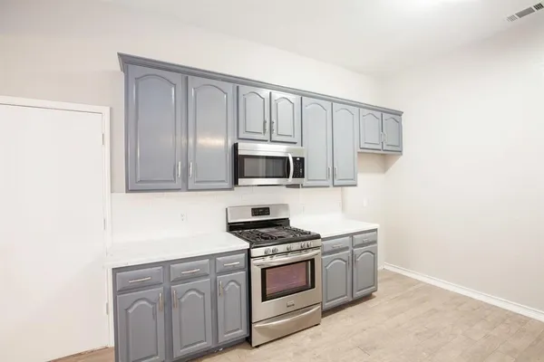 a kitchen with stainless steel appliances granite countertop white cabinets and stove top oven