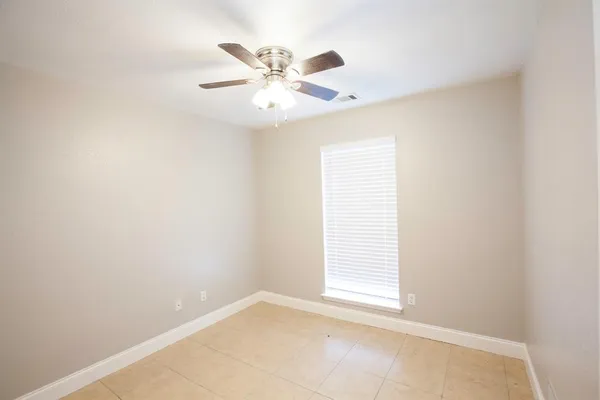 an empty room with windows and fan