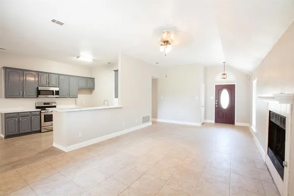 a view of a kitchen with a sink stove cabinets and empty room