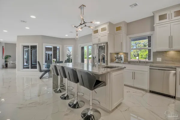 a kitchen with stainless steel appliances granite countertop a stove top oven a sink dishwasher a dining table and chairs with wooden floor