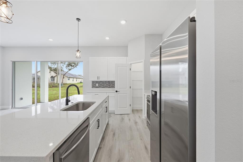 13975 Southwest 27 Ct Road Ocala, FL 34473 - Photo 13 of 35 a kitchen with stainless steel appliances granite countertop a refrigerator a sink a stove and a wooden floors