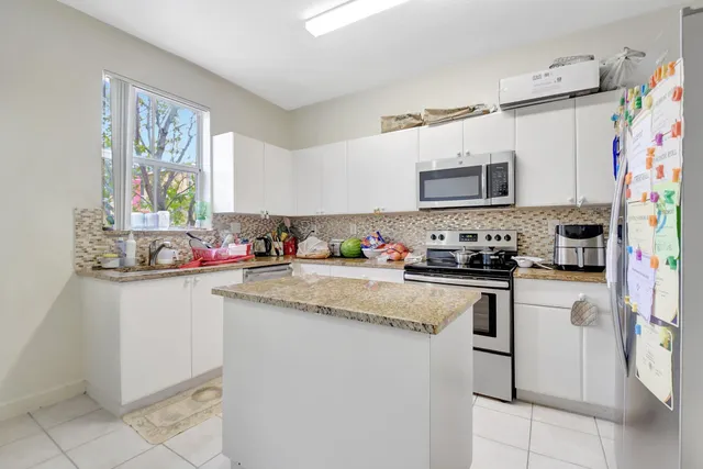 a kitchen with granite countertop a sink stainless steel appliances and white cabinets