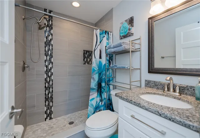 a bathroom with a granite countertop sink a toilet and shower