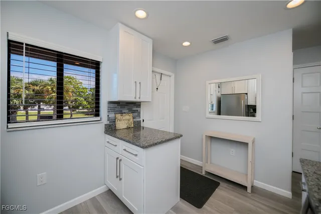 a kitchen with white cabinets and window