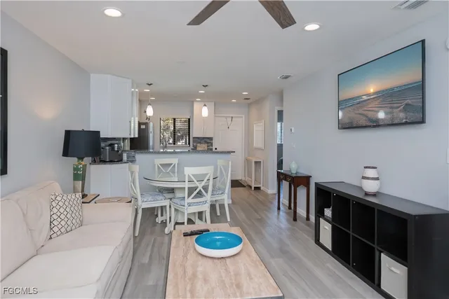 a living room with furniture a flat screen tv and kitchen view