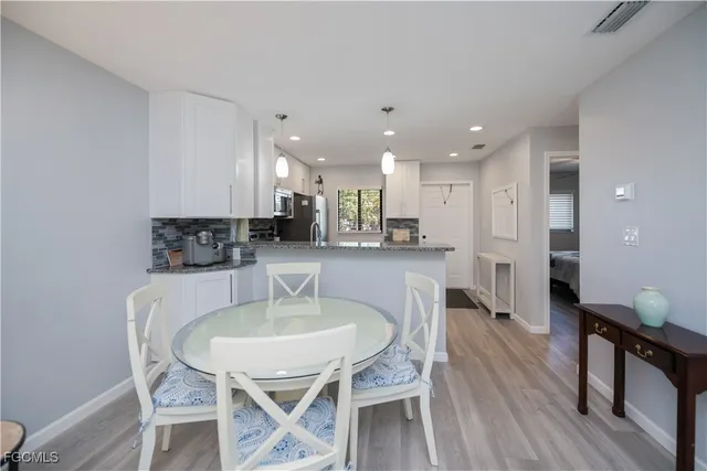 a kitchen with kitchen island stainless steel appliances a dining table chairs sink and cabinets
