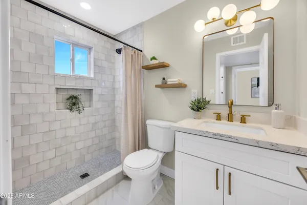 a bathroom with a granite countertop sink a toilet and shower