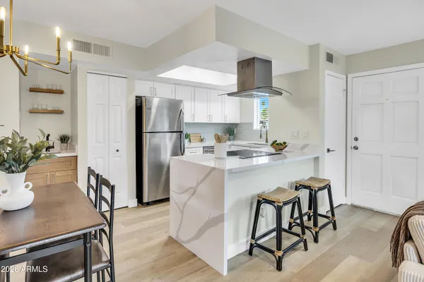 a kitchen with stainless steel appliances a refrigerator a stove a sink and chairs