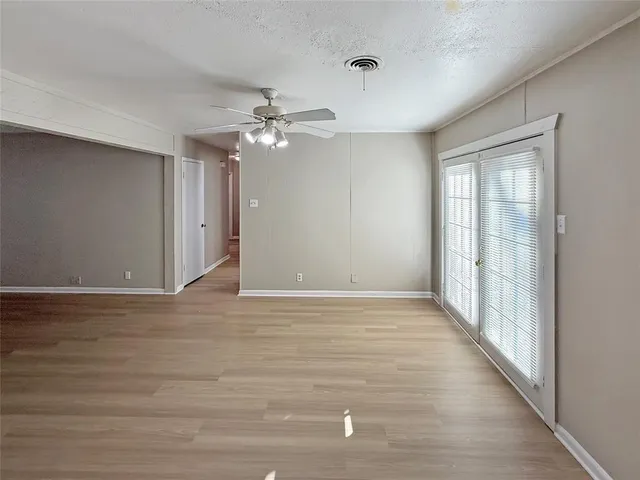 an empty room with windows and fan