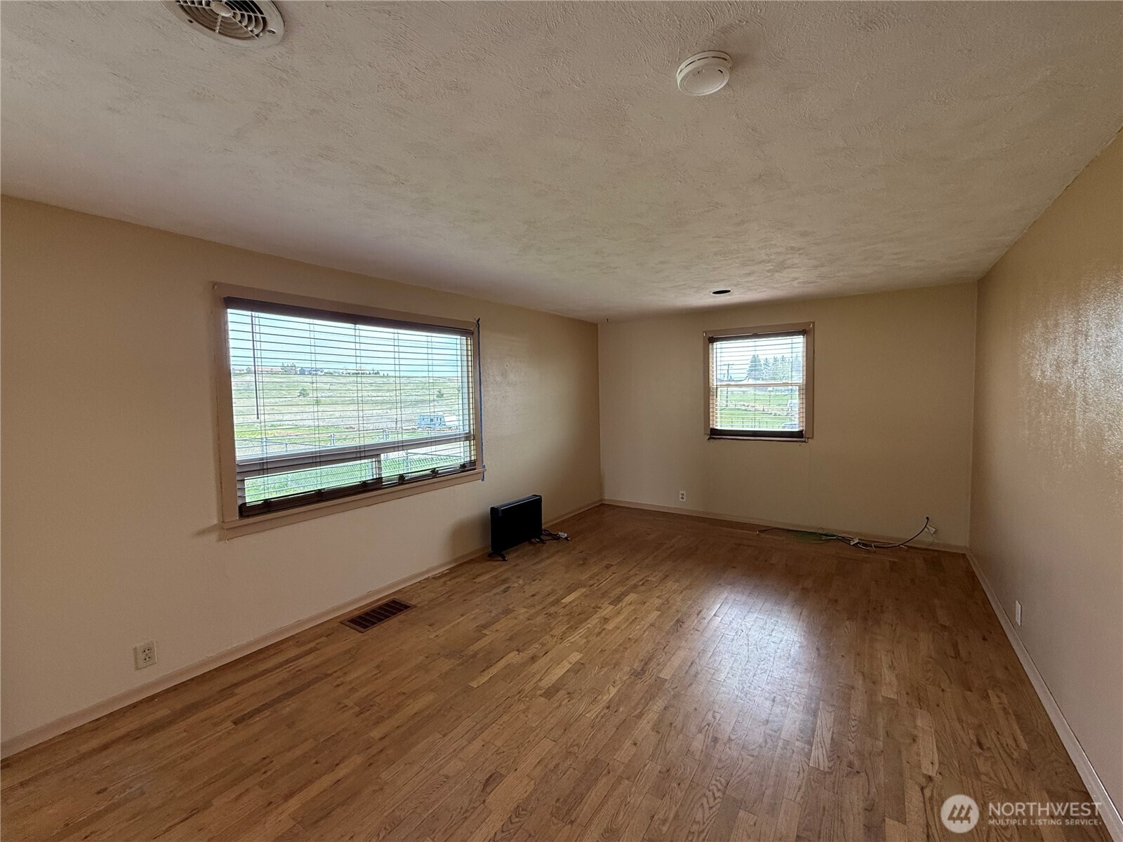 306 South Adams Street Waterville, WA 98858 - Photo 3 of 25 an empty room with wooden floor and windows