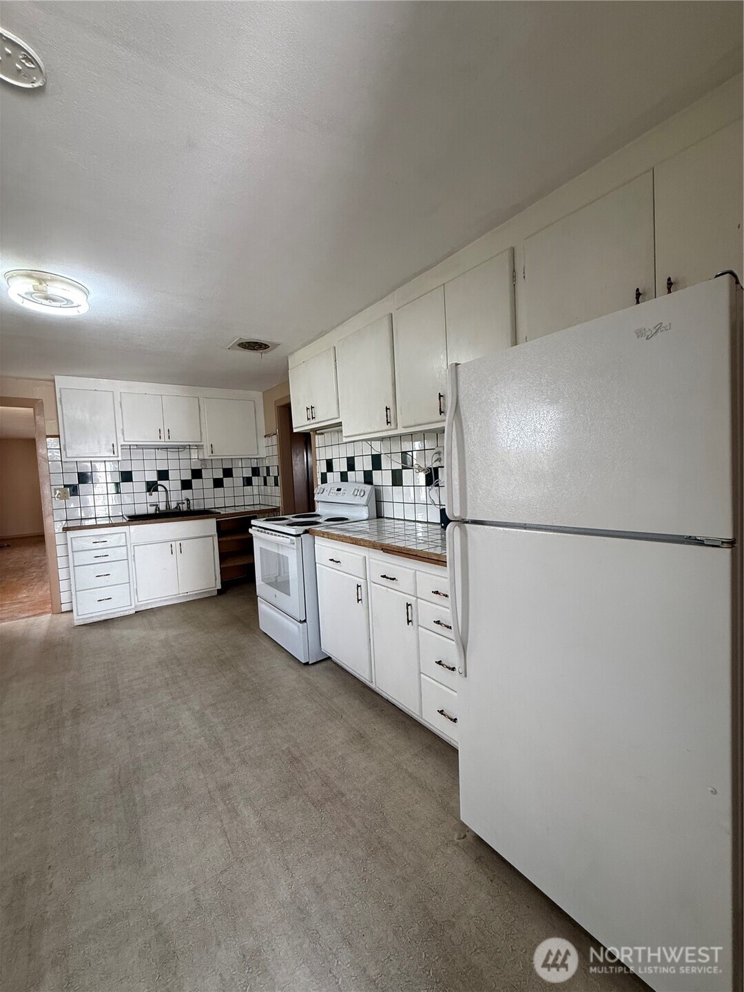 306 South Adams Street Waterville, WA 98858 - Photo 7 of 25 a kitchen with stainless steel appliances a refrigerator sink and white cabinets