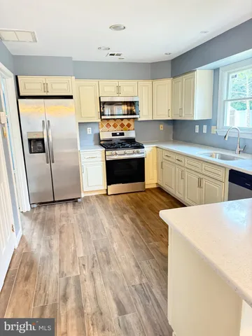 a kitchen with granite countertop a refrigerator oven a sink dishwasher and wooden cabinets