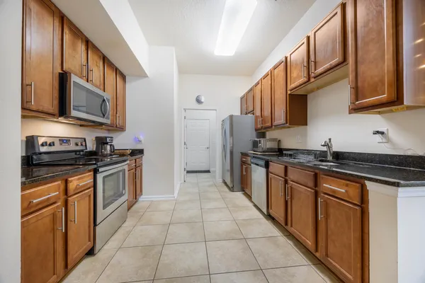 a large kitchen with stainless steel appliances granite countertop a stove top oven a sink dishwasher and a refrigerator