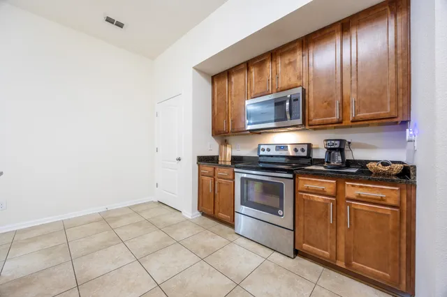 a kitchen with granite countertop a stove top oven microwave and cabinets