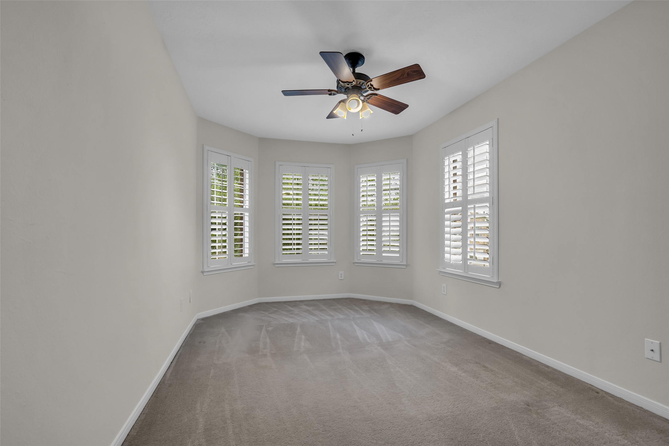 6807 Chapelfield Lane Houston, TX 77049 - Photo 33 of 42 This room features a neutral color palette with carpeted flooring, a ceiling fan with light, and multiple windows with shutters, offering ample natural light.