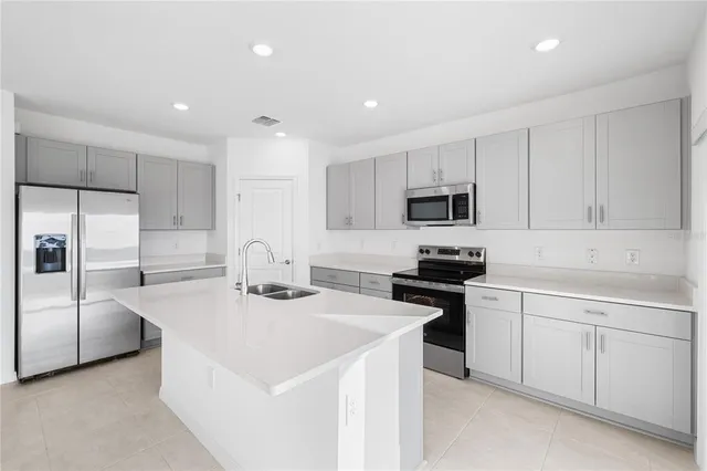 a kitchen with kitchen island a sink a stove and cabinets