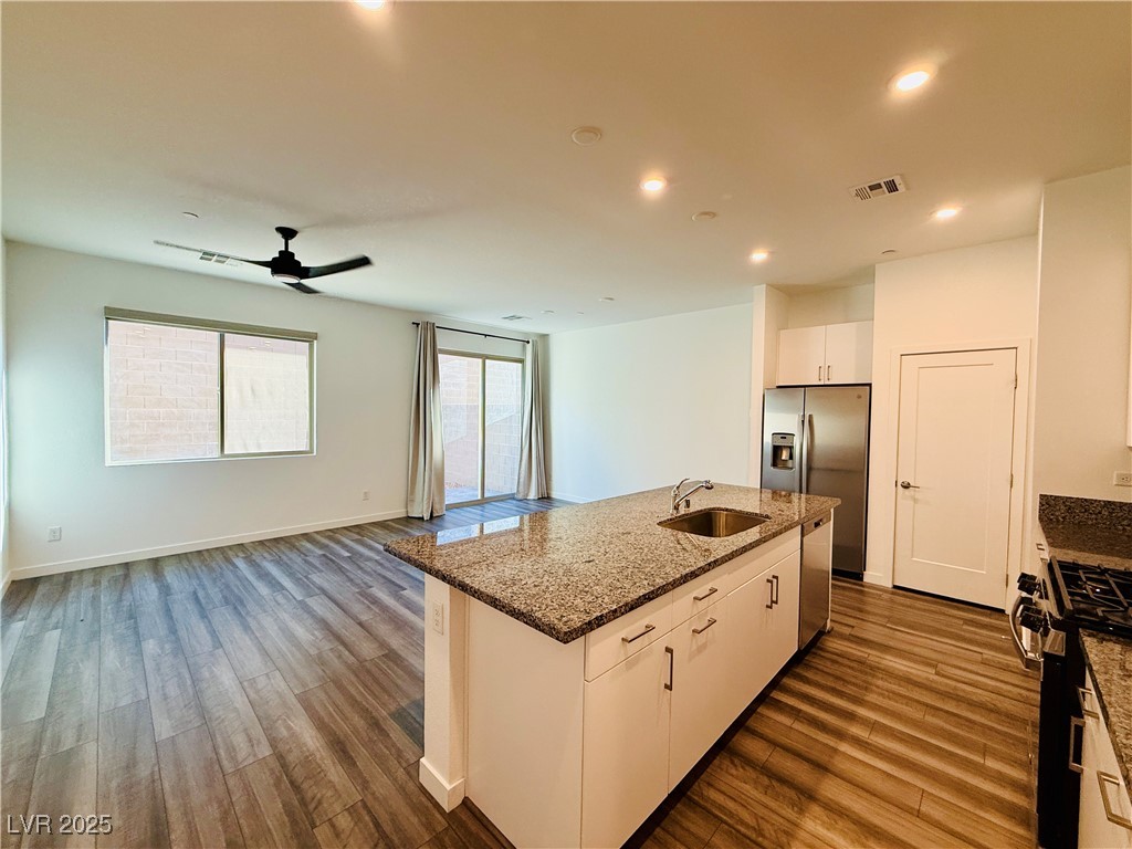 3219 Timorasso Avenue Henderson, NV 89044 - Photo 27 of 27 Kitchen featuring dark stone countertops, open floor plan, dark wood finished floors, white cabinets, and appliances with stainless steel finishes