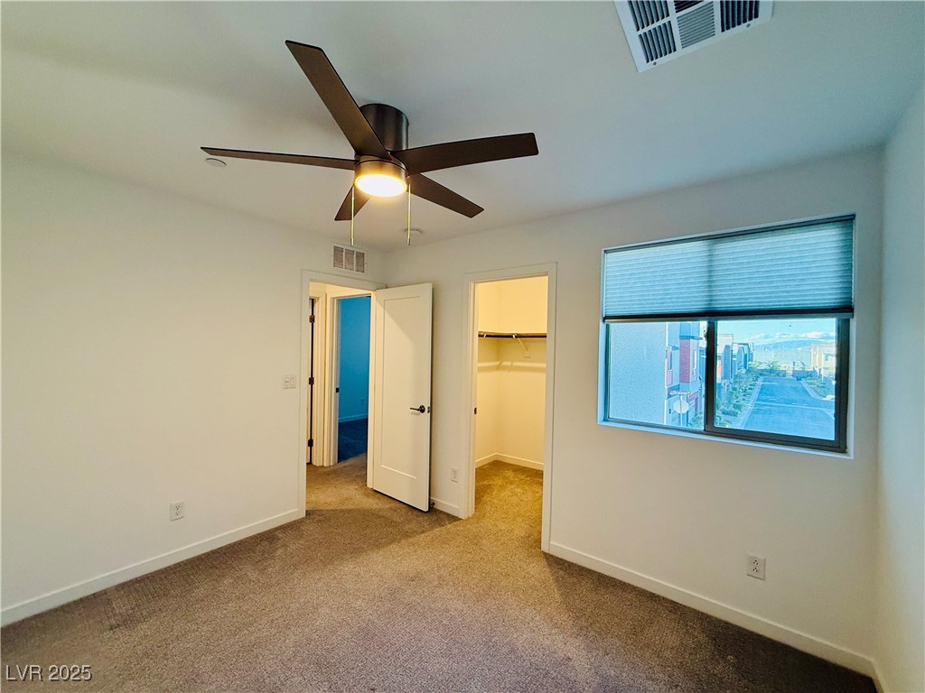 3219 Timorasso Avenue Henderson, NV 89044 - Photo 19 of 27 Unfurnished bedroom with carpet flooring, a walk in closet, and a ceiling fan