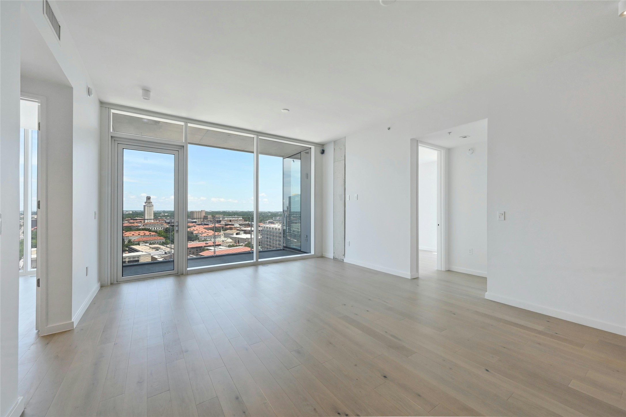 313 West 17th Street, Unit 2101 Austin, TX 78701 - Photo 2 of 36 Expansive living space with wide-plank oak flooring, floor-to-ceiling windows, and uninterrupted views of the UT Tower and city skyline. Step onto your private balcony and take in the best of downtown Austin living.
