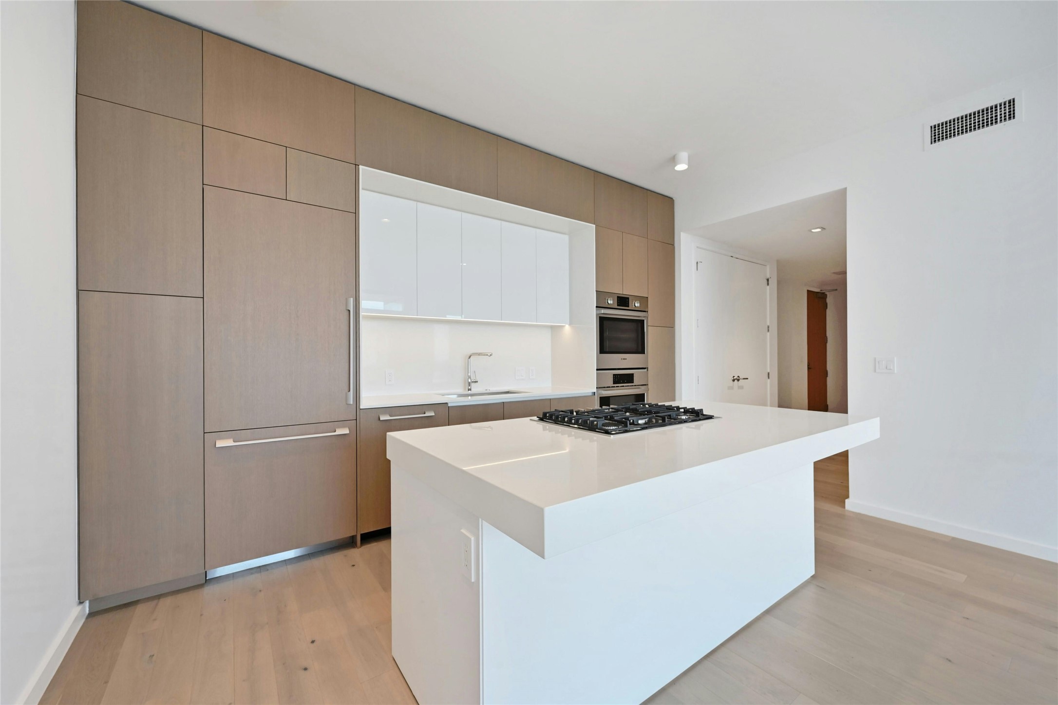 313 West 17th Street, Unit 2101 Austin, TX 78701 - Photo 5 of 36 A streamlined culinary space highlighted by Bosch appliances, a gas cooktop built into the expansive quartz island, and custom cabinetry that seamlessly conceals the refrigerator and dishwasher for a clean, modern aesthetic.