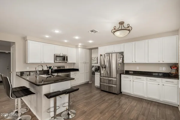 a kitchen with granite countertop a refrigerator stove microwave and cabinets