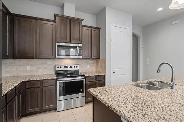 a kitchen with granite countertop a sink a counter and stainless steel appliances