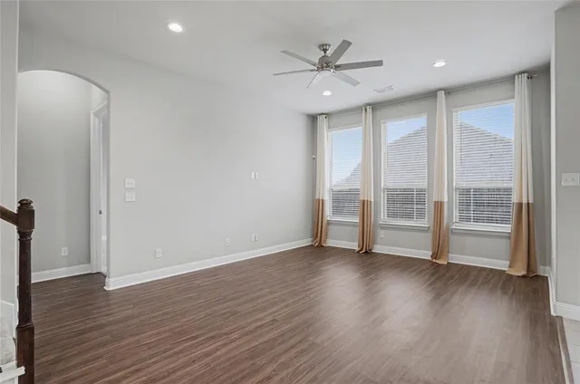 a view of an empty room with wooden floor and a kitchen