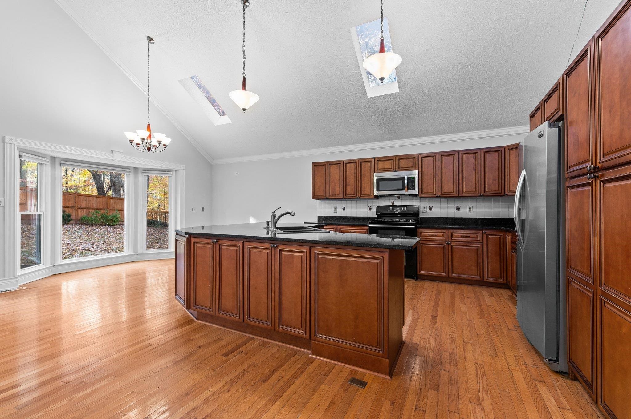 5808 Glenfiddich Way Raleigh, NC 27613 - Photo 36 of 64 a kitchen with stainless steel appliances granite countertop wooden floors a stove and a microwave