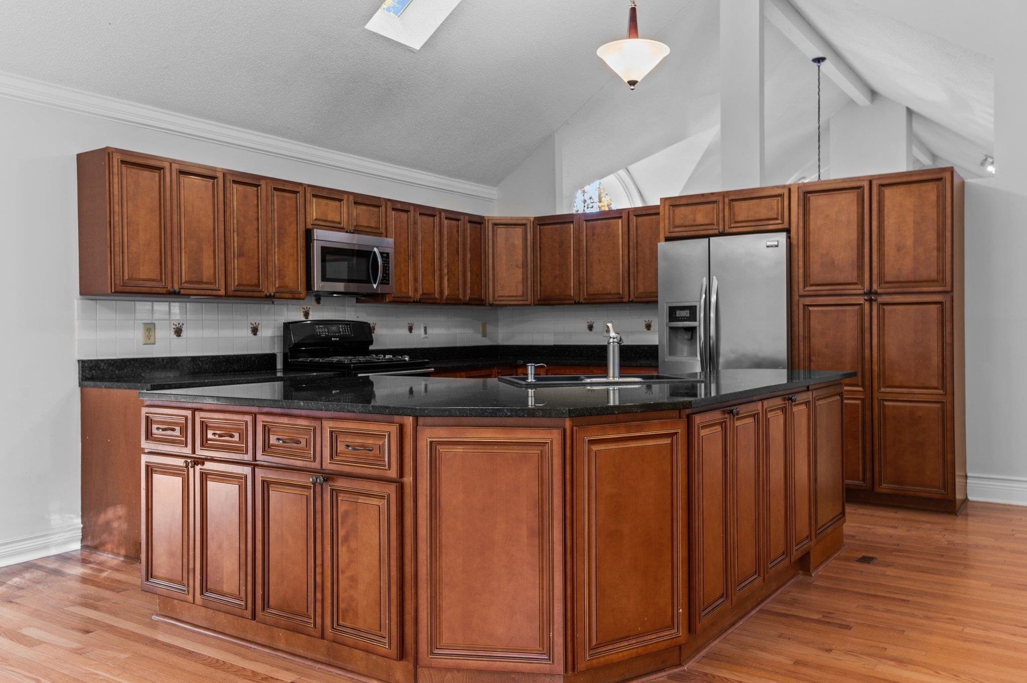 5808 Glenfiddich Way Raleigh, NC 27613 - Photo 40 of 64 a kitchen with stainless steel appliances granite countertop a refrigerator a sink a stove a microwave and wooden cabinets