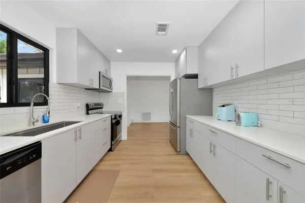 a large kitchen with stainless steel appliances lots of counter space and a sink