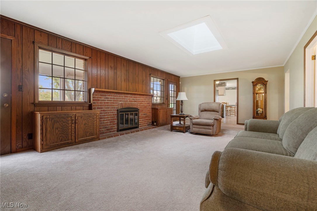 14265 Reeder Avenue Northeast Alliance, OH 44601 - Photo 11 of 39 Living area featuring light colored carpet, wood walls, a skylight, a fireplace, and crown molding
