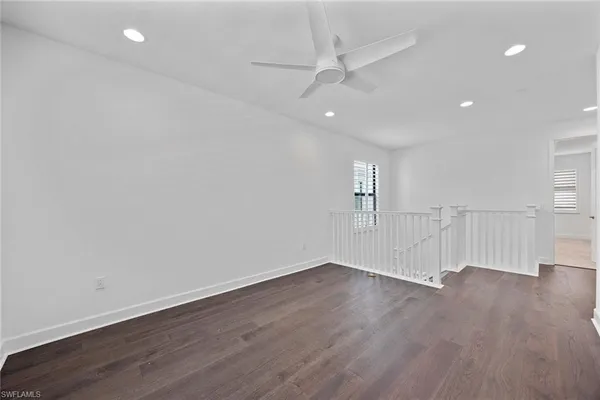 an empty room with wooden floor fan and window