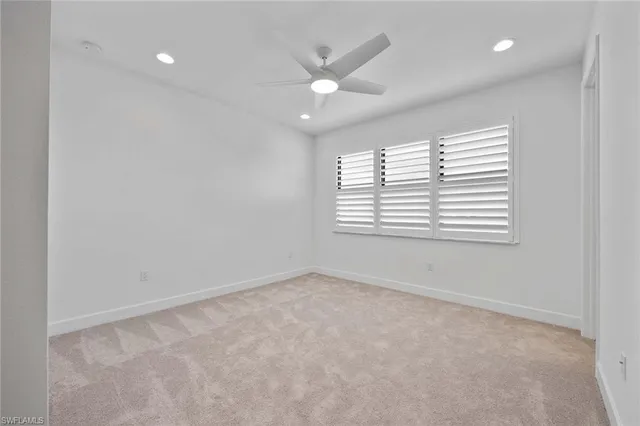 an empty room with windows and ceiling fan