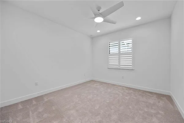 an empty room with windows and ceiling fan