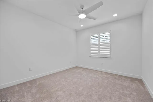 an empty room with windows and ceiling fan
