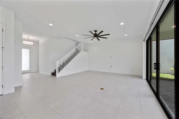 an empty room with staircase and a ceiling fan