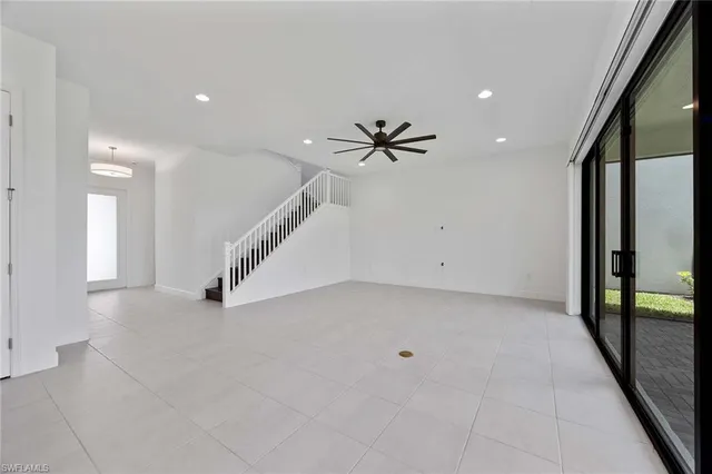 an empty room with staircase and a ceiling fan