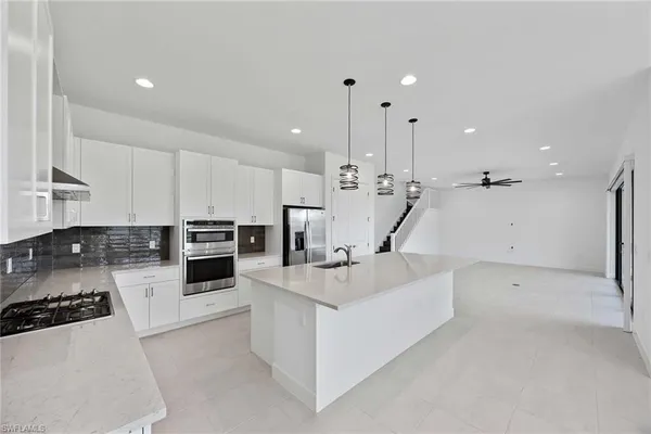 a large white kitchen with a stove a sink and a refrigerator