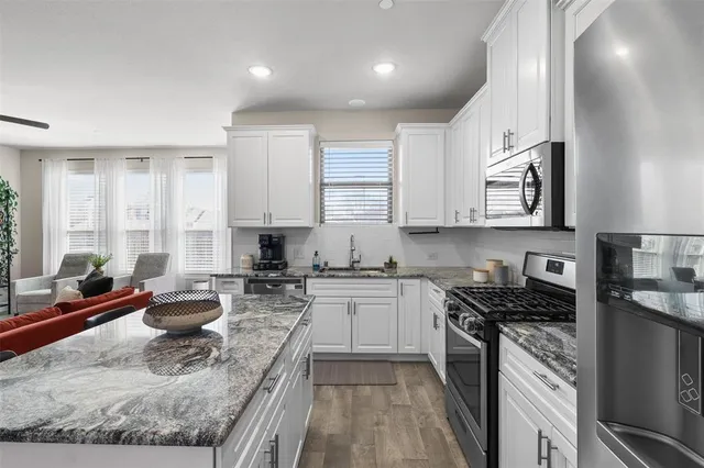 a kitchen with stainless steel appliances granite countertop sink stove top oven and cabinets