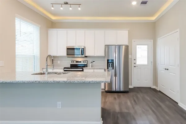 a kitchen with stainless steel appliances granite countertop a refrigerator a stove a sink and a granite counter tops with wooden floors