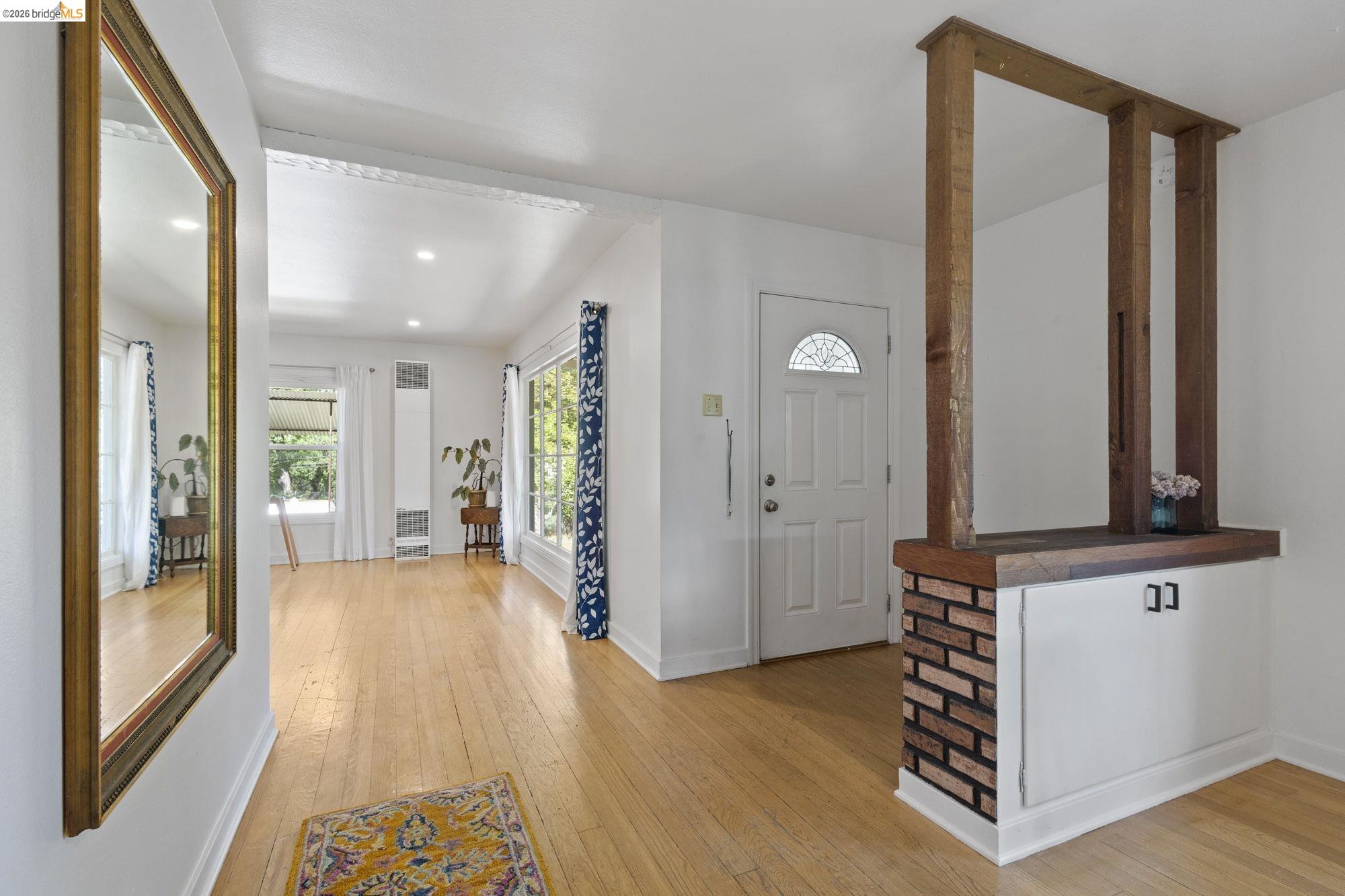 18363 Yosemite Road Tuolumne, CA 95379 - Photo 3 of 34 Entryway featuring wood-finish flooring, a white paneled door with an arched glass insert, and a partial brick accent wall with wood-finish trim