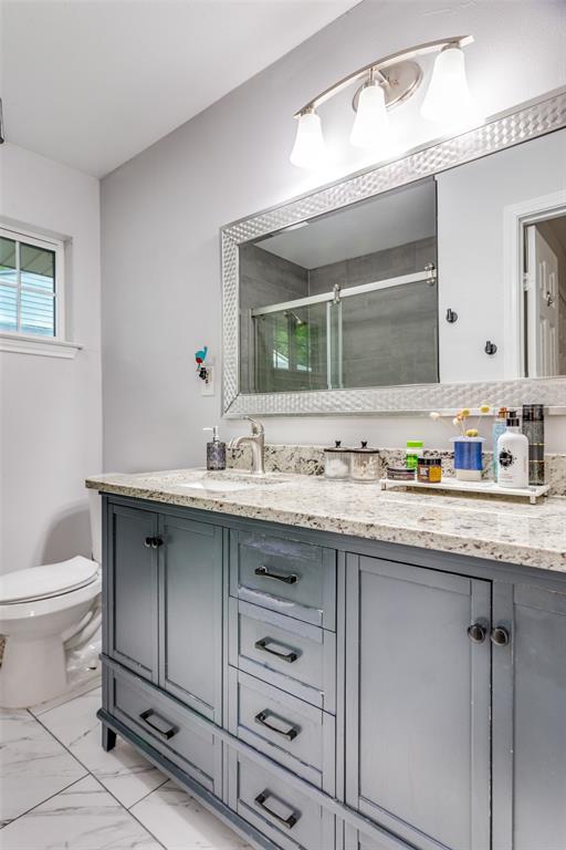 6921 Valhalla Road Fort Worth, TX 76116 - Photo 17 of 25 Bathroom with double vanity, a stall shower, and light marble finish flooring
